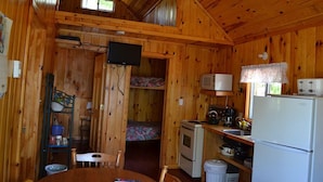Une petite cabine comprenant une cuisine, un coin repas et un lit superposé.