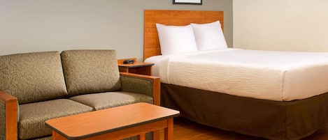Une chambre d’hôtel avec un lit, un canapé, une petite table et une table de chevet.