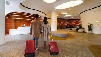 A modern lobby with a reception desk, seating areas, and a check-in counter.