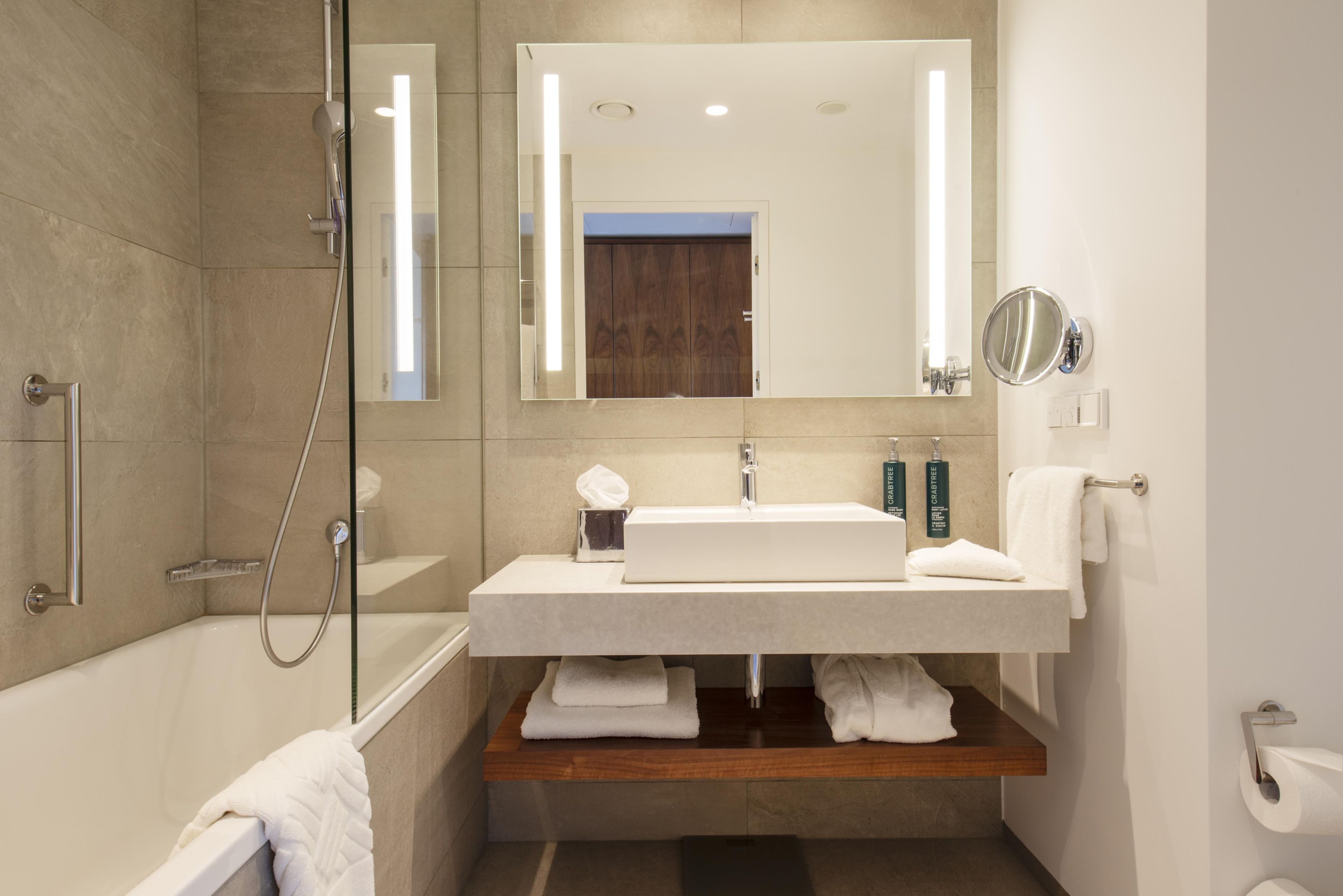 Un baño moderno con bañera, lavamanos, espejo y ducha.