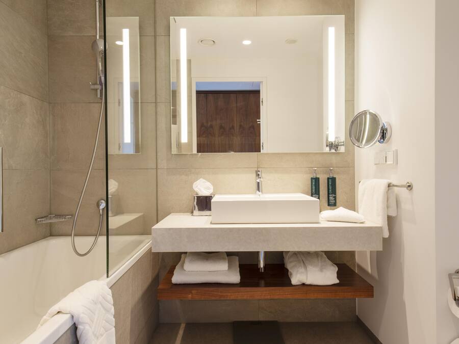 Un baño moderno con bañera, lavamanos, espejo y ducha.