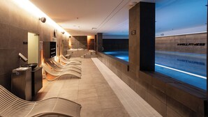 Et moderne spaområde med opvarmet pool, siddepladser og et skilt, der angiver placeringen.