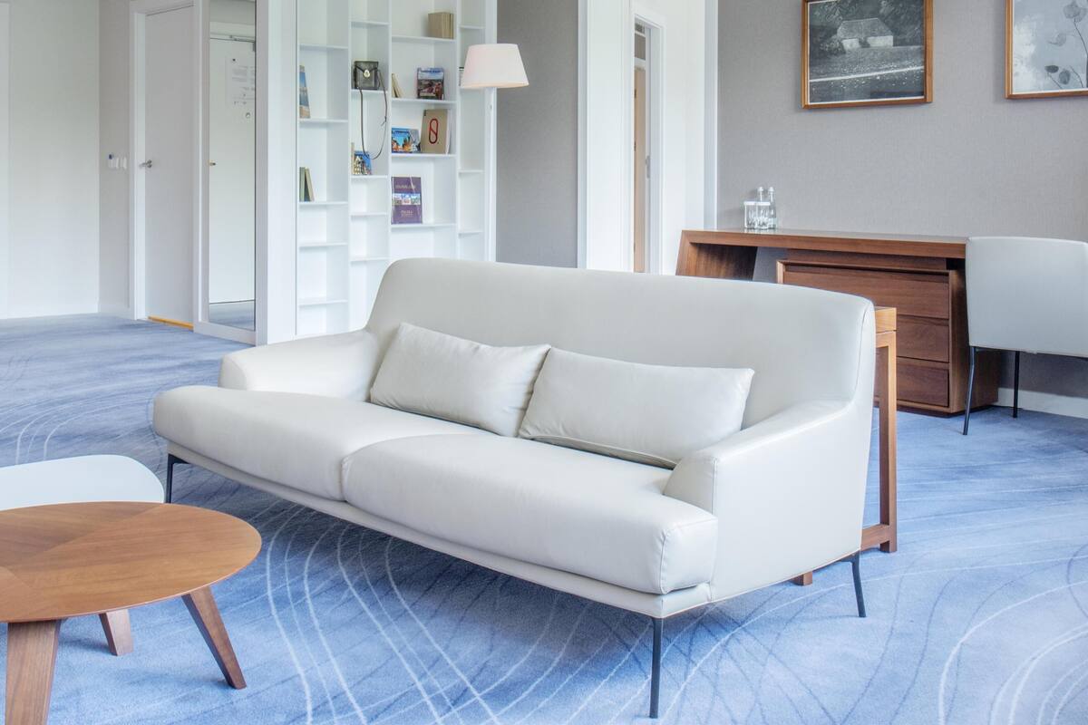 Una sala de estar moderna con un sofá de cuero blanco, una mesa de centro de madera y un escritorio con una silla.