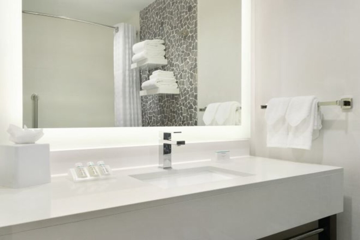 Un baño moderno con un lavabo blanco, un espejo y un perchero para toallas.