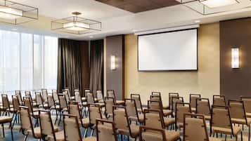 A conference room with rows of chairs, a projector screen, and ambient lighting.