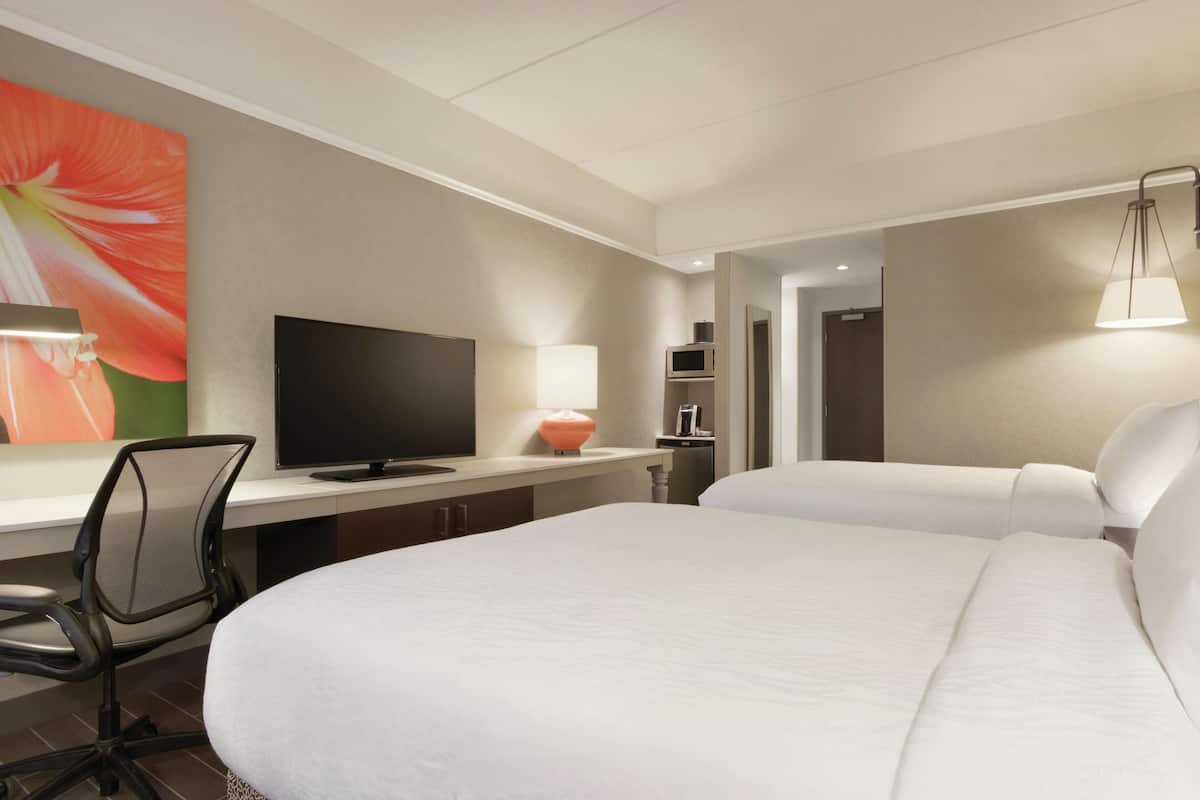 Une chambre d’hôtel avec un lit, un bureau avec une télévision, une chaise et une lampe.
