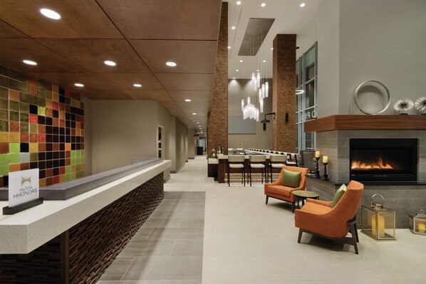 A modern lobby with a reception desk, seating area, and a fireplace.