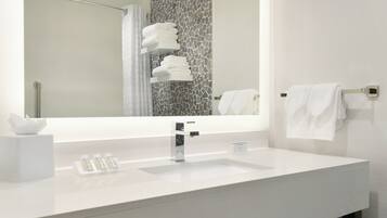 Un baño moderno con un lavamanos blanco, un espejo grande y un perchero para toallas.