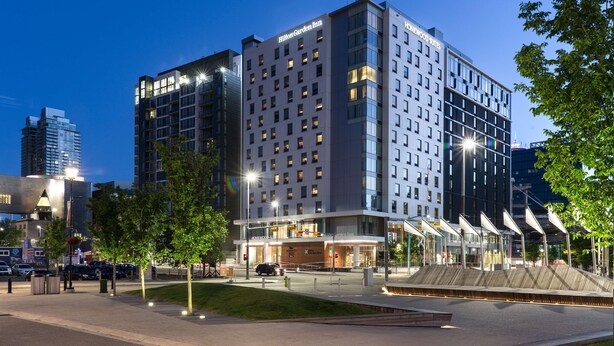 A modern hotel with multiple floors, a prominent entrance, and a well-lit facade. - Homewood Suites by Hilton Calgary Downtown (Calgary)