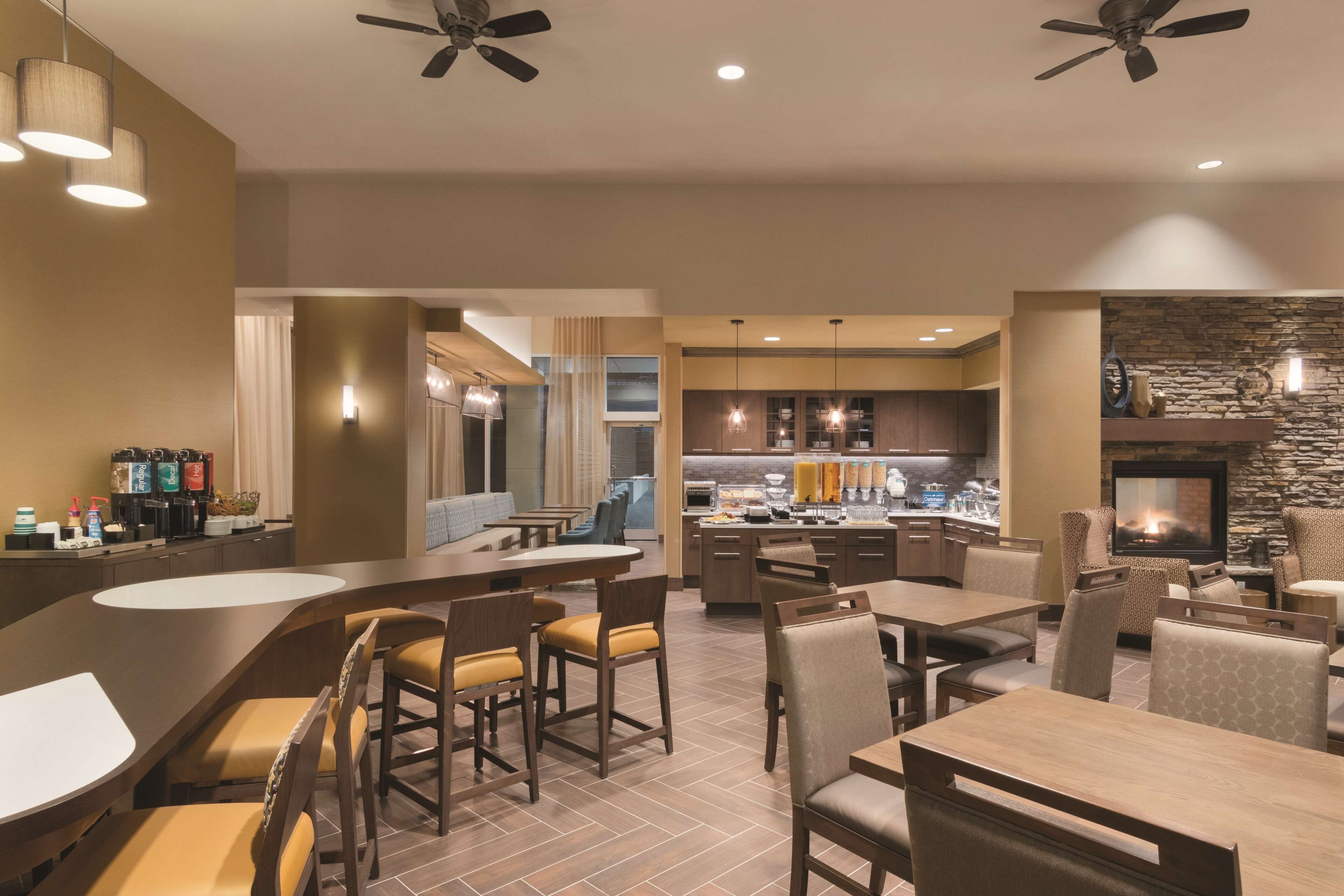 A modern hotel lobby with a bar area, seating, and a kitchen in the background.