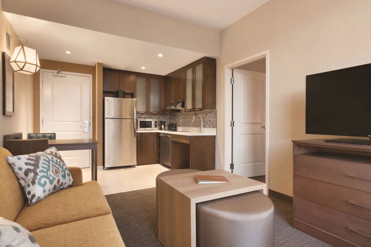 Una sala de estar moderna con un sofá, un reposapiés y un televisor de pantalla plana.