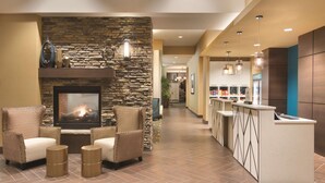 A modern lobby with a stone fireplace, comfortable seating, and a reception area. - Homewood Suites by Hilton Calgary Downtown (Calgary)