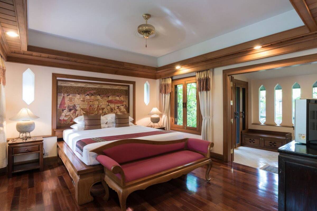 Ein geräumiges Schlafzimmer mit einem großen Bett, einer hölzernen Bank und einem Deckenventilator.