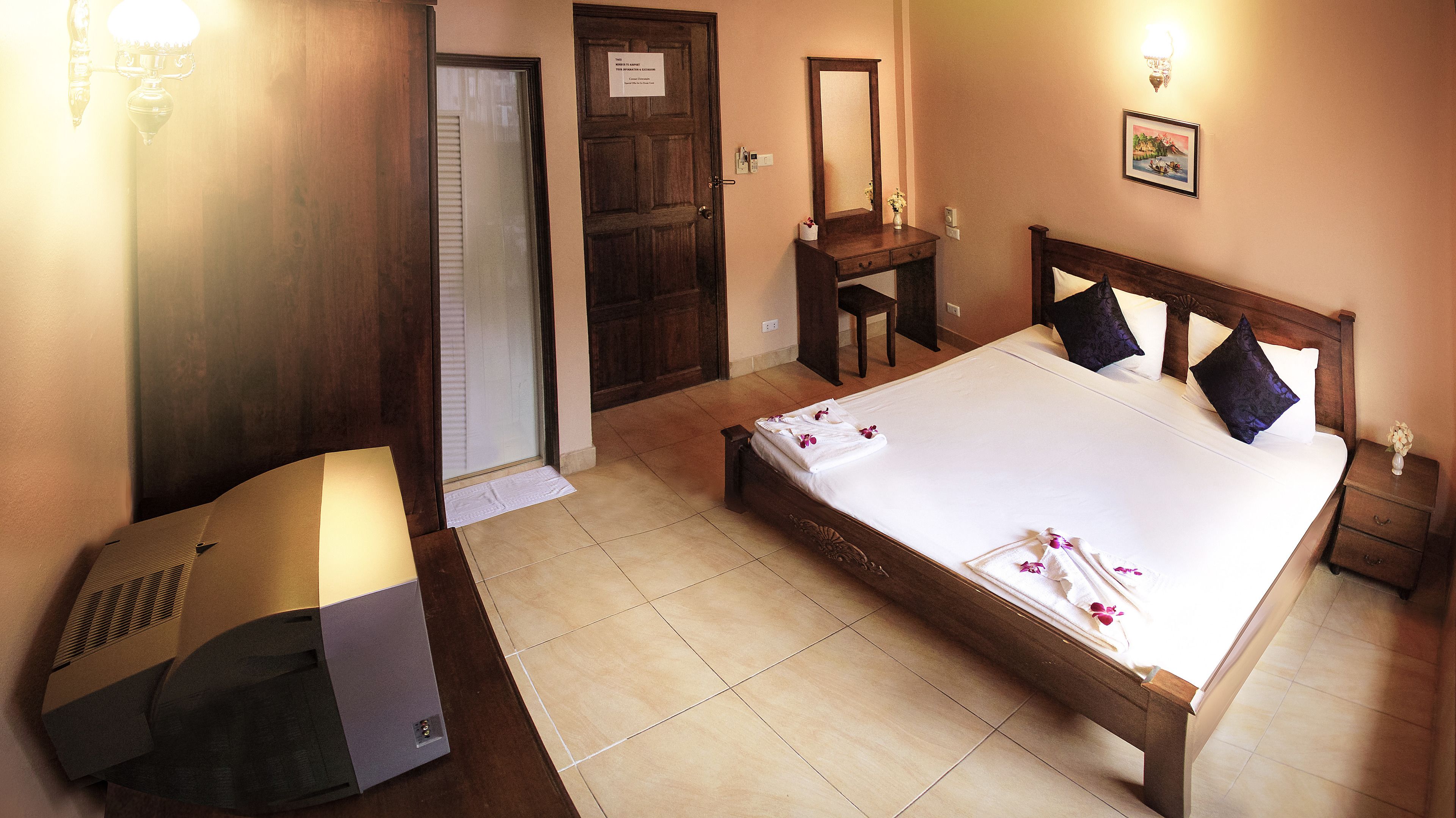 A hotel room with a bed, bedside table, nightstand, and a mirror.