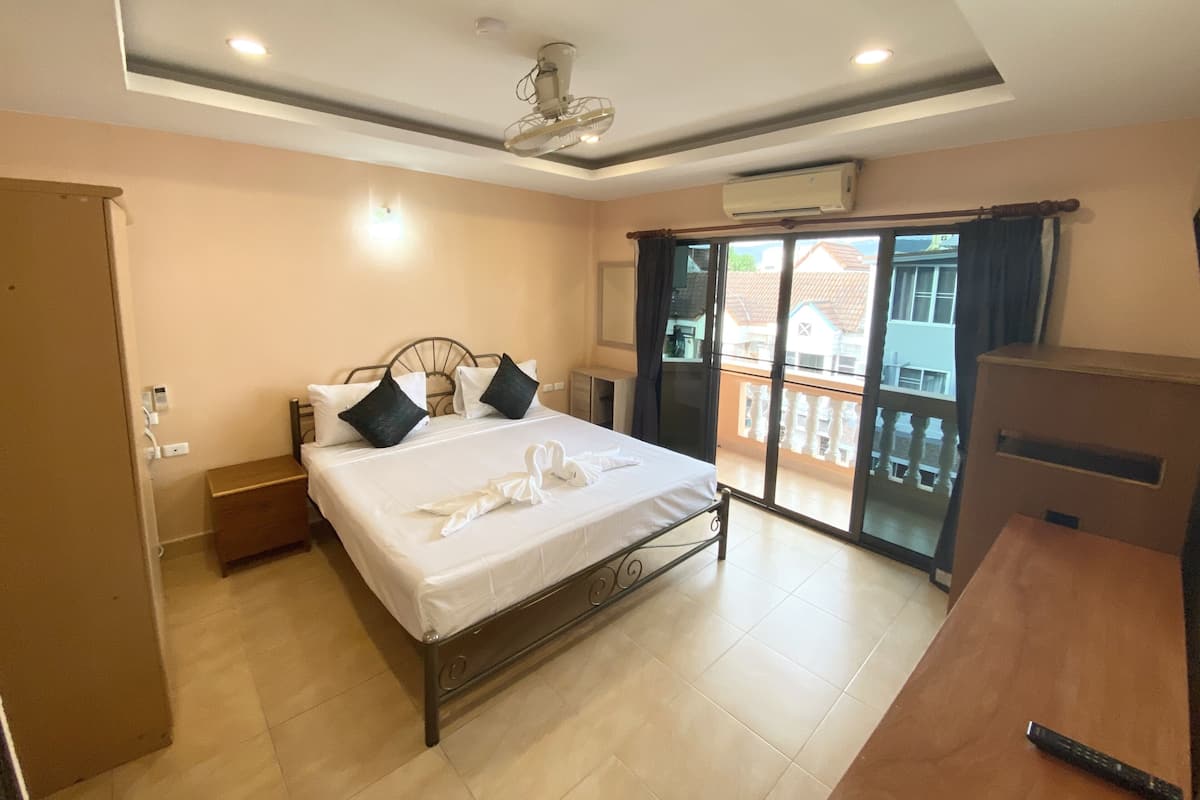 Una habitación de hotel con cama, escritorio, balcón y vistas, además de un ventilador de techo.