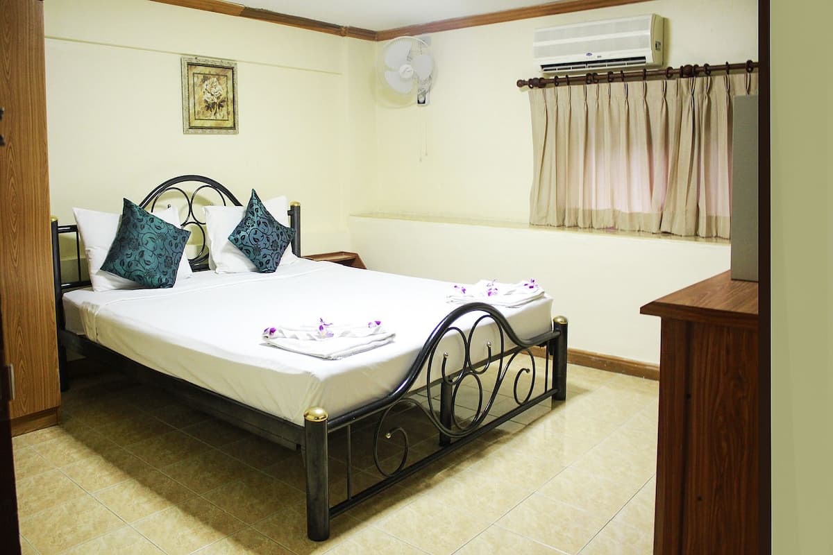 Una habitación de hotel con una cama, mesita de noche y un aire acondicionado.