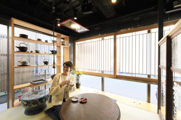 A room with a large window, a wooden table, and shelves with various items. - Andon Ryokan (Tokyo)