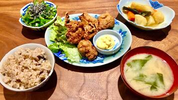 A table with various dishes including fried chicken, rice, a salad, and a bowl of soup.
