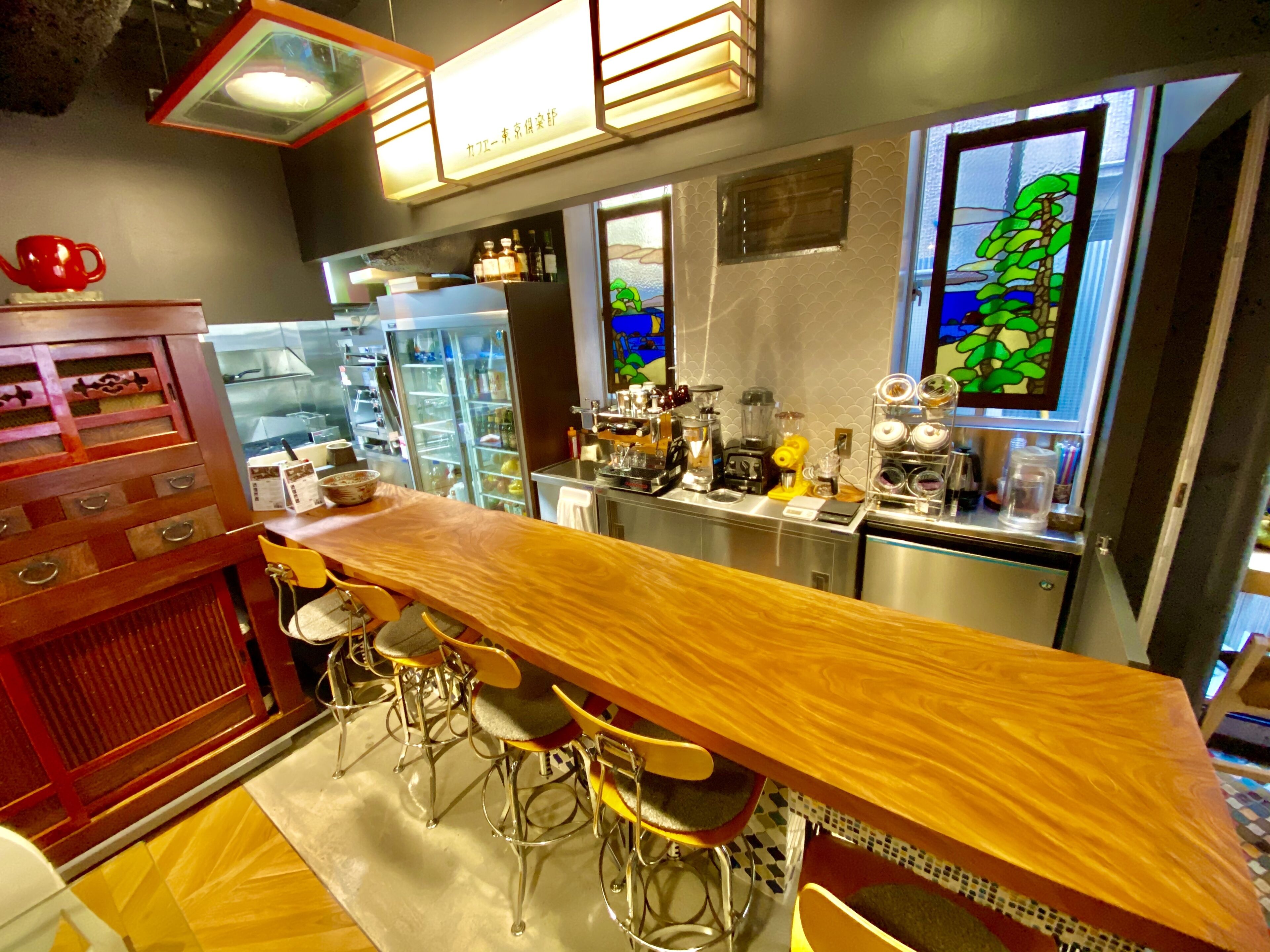 A modern kitchen with a long wooden bar, stainless steel appliances, and a decorative window with a green landscape view.