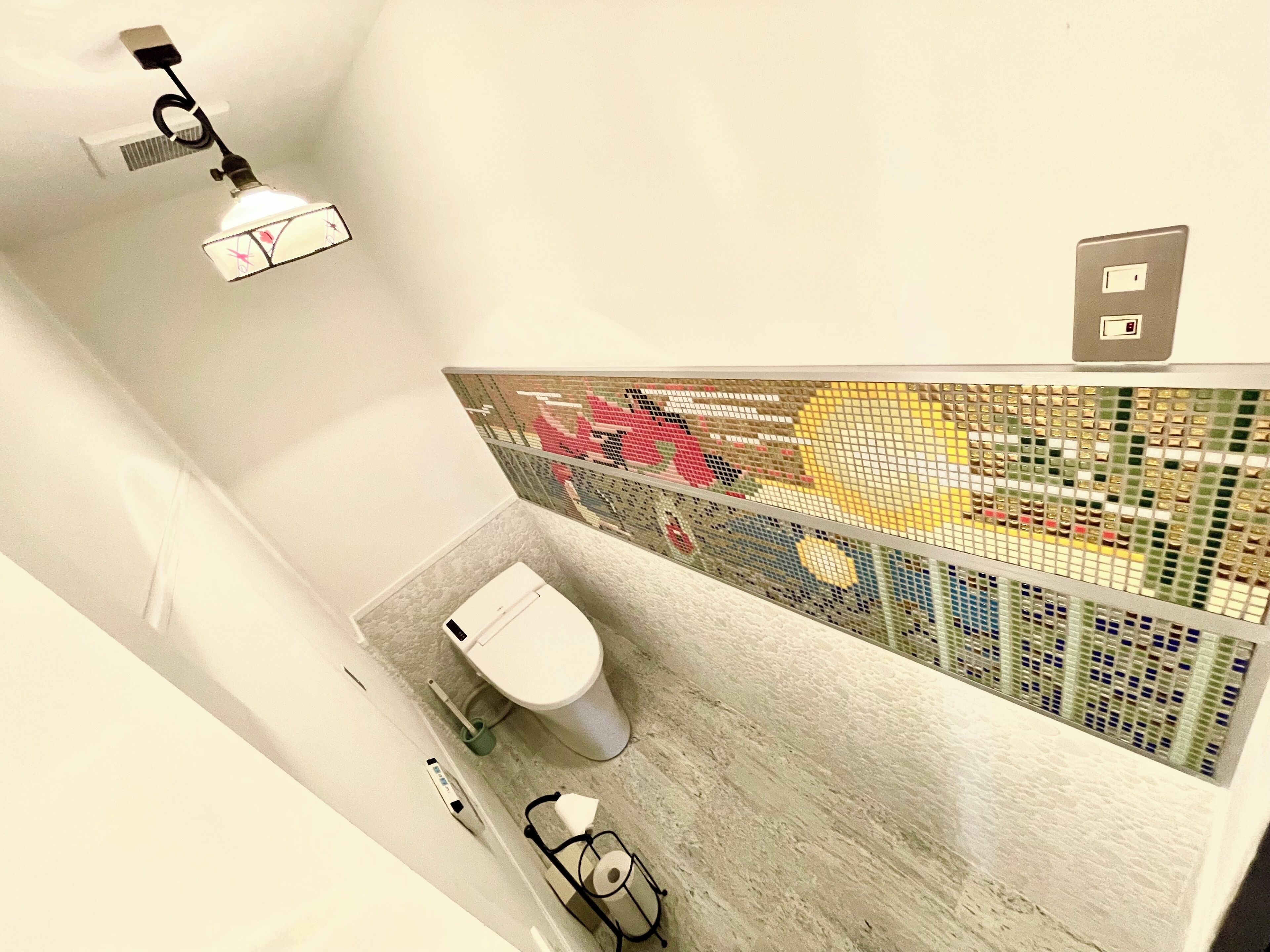 A modern bathroom with a toilet, a hand dryer, and a shower area.
