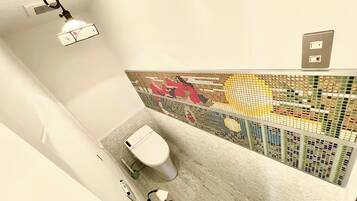 A modern bathroom with a toilet, a hand dryer, and a shower area.