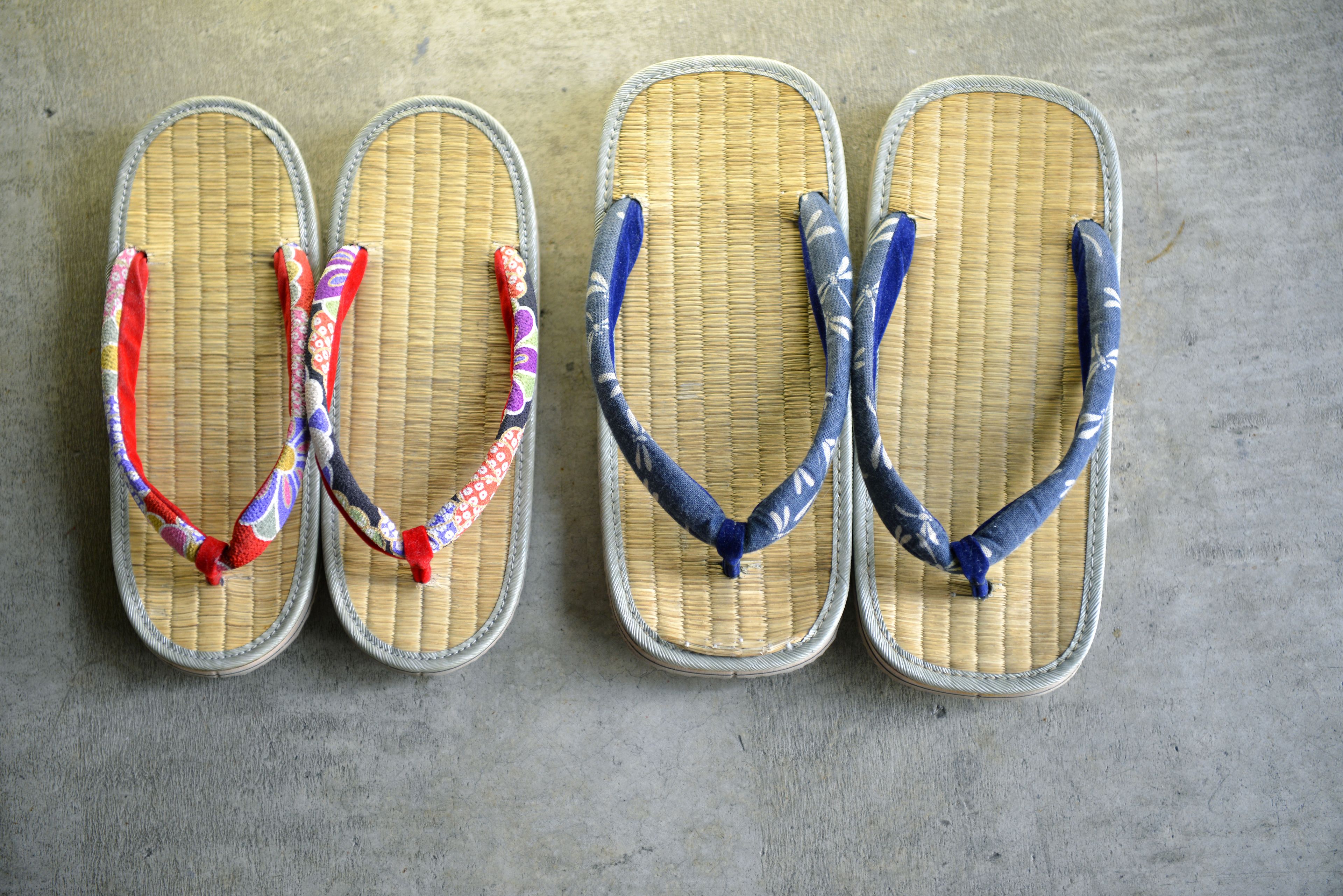 Four pairs of flip-flops with different colored straps laid out on a concrete floor.