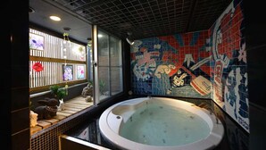 Un baño con una bañera grande, un mural de azulejos y una ventana con vistas al exterior.