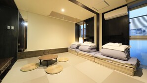 Una habitación moderna con esteras de tatami, una mesa de madera baja y un futón con almohadas.