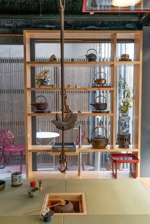 A traditional Japanese room with tatami flooring, a wooden shelf with tea utensils, and a view of a cityscape through a shoji screen. - Andon Ryokan (Tokyo)