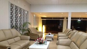 Una sala moderna con sofás de cuero color beige, una mesa de centro blanca y un jarrón decorativo.