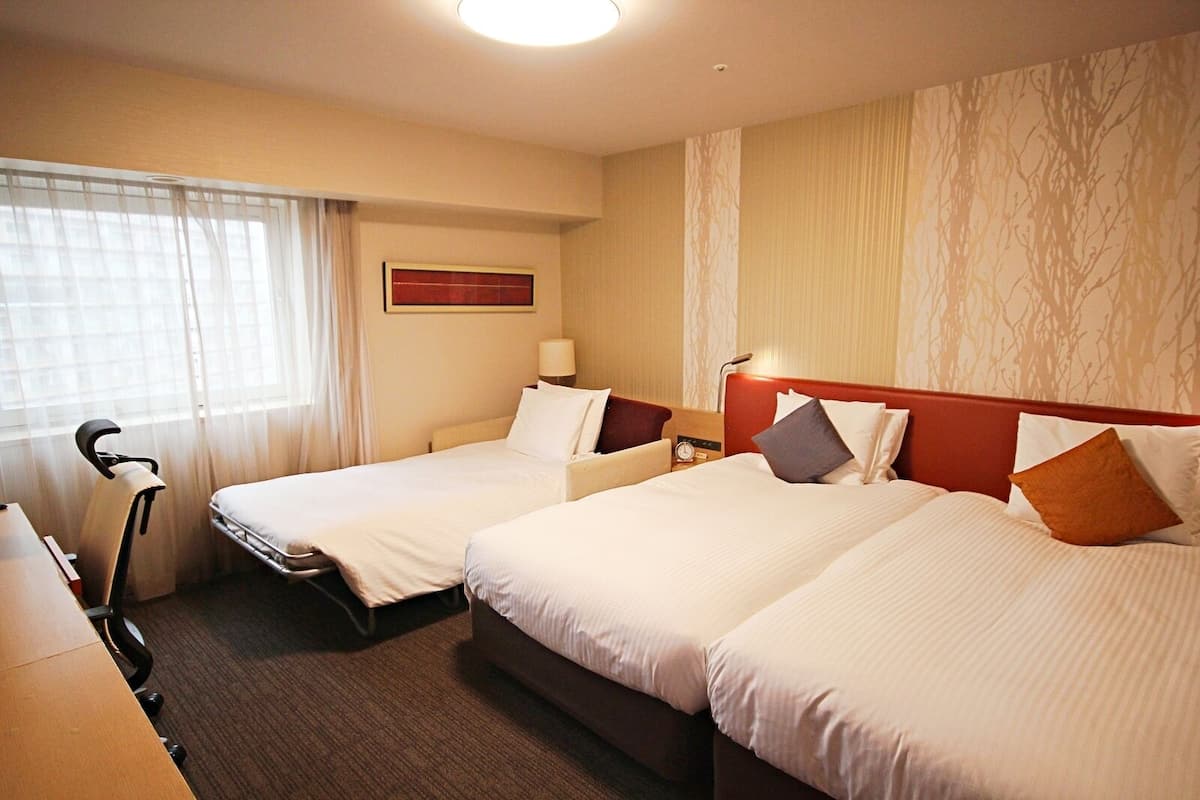 Een hotelkamer met twee bedden, een bureau, een stoel en een loopband.