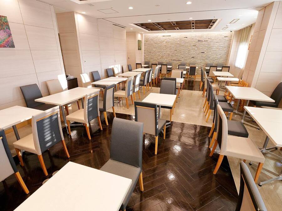 A conference room with multiple tables and chairs, a stone wall, and a painting on the wall.