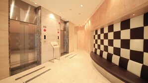 A modern lobby with a checkered wall, a marble elevator, and a seating area. - Richmond Hotel Premier Musashikosugi (Kawasaki)