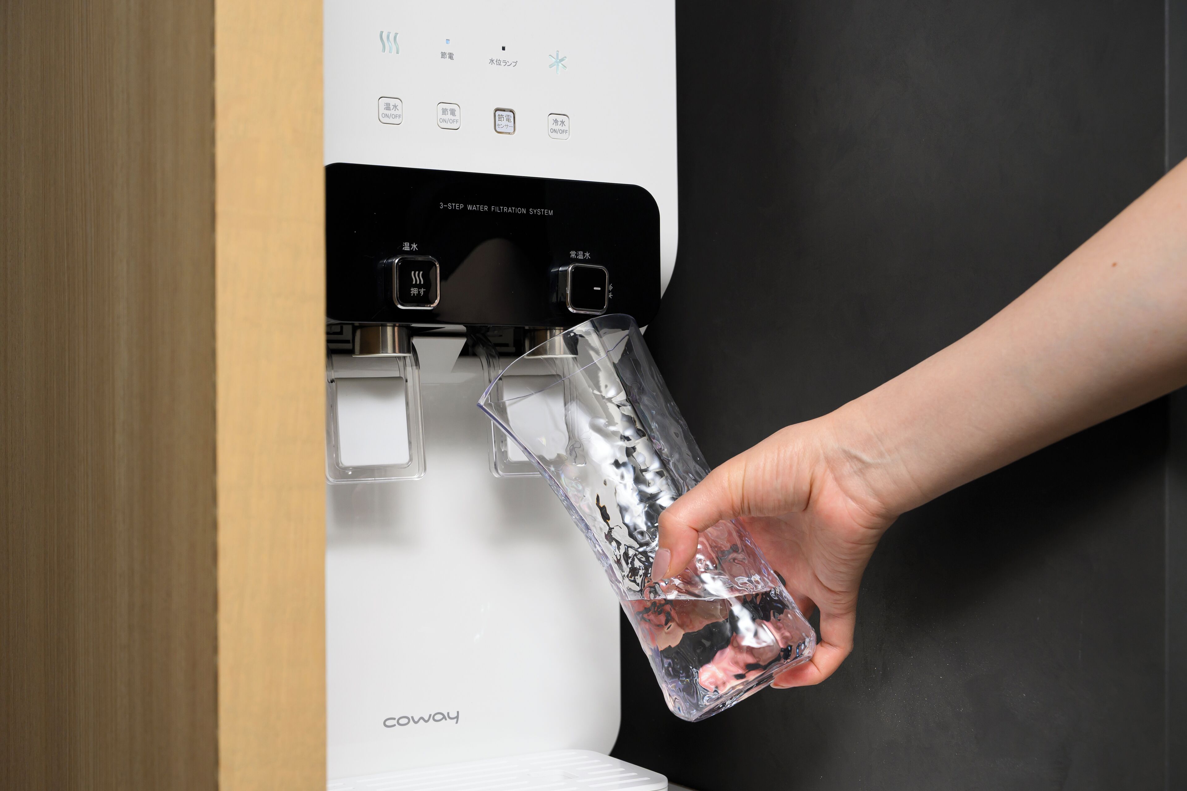 A water filtration system with a hand filling a bottle.