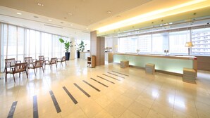 A spacious lobby with a reception desk, seating area, and large windows offering views of the city. - Richmond Hotel Premier Musashikosugi (Kawasaki)