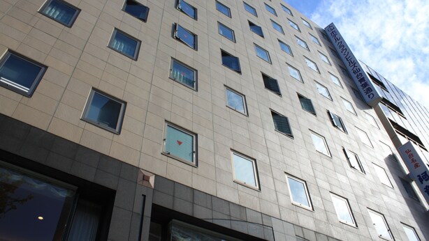 A multi-story building with a modern architectural design, featuring a grid of windows and a prominent sign on the side. - Hotel Crown Hills Sendai Aobadori (Sendai)