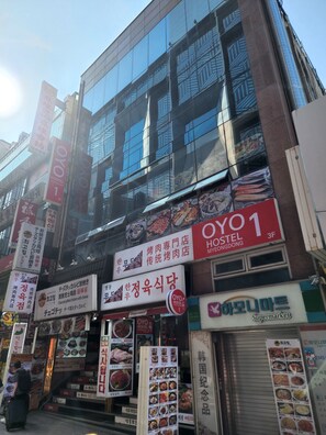 Un edificio de varios pisos con varios letreros, incluyendo un hostal llamado "OYO 1" y un supermercado.