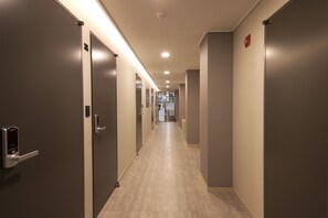 A hallway with doors on both sides, recessed lighting, and a tiled floor.