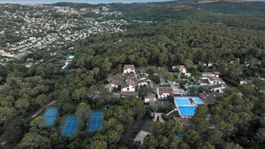 An aerial view of a residential area with dense tree coverage, a small cluster of houses, and a tennis court. - Belambra Clubs La Colle-sur-Loup - Les Terrasses De Saint-Paul De Vence (La Colle-sur-Loup)