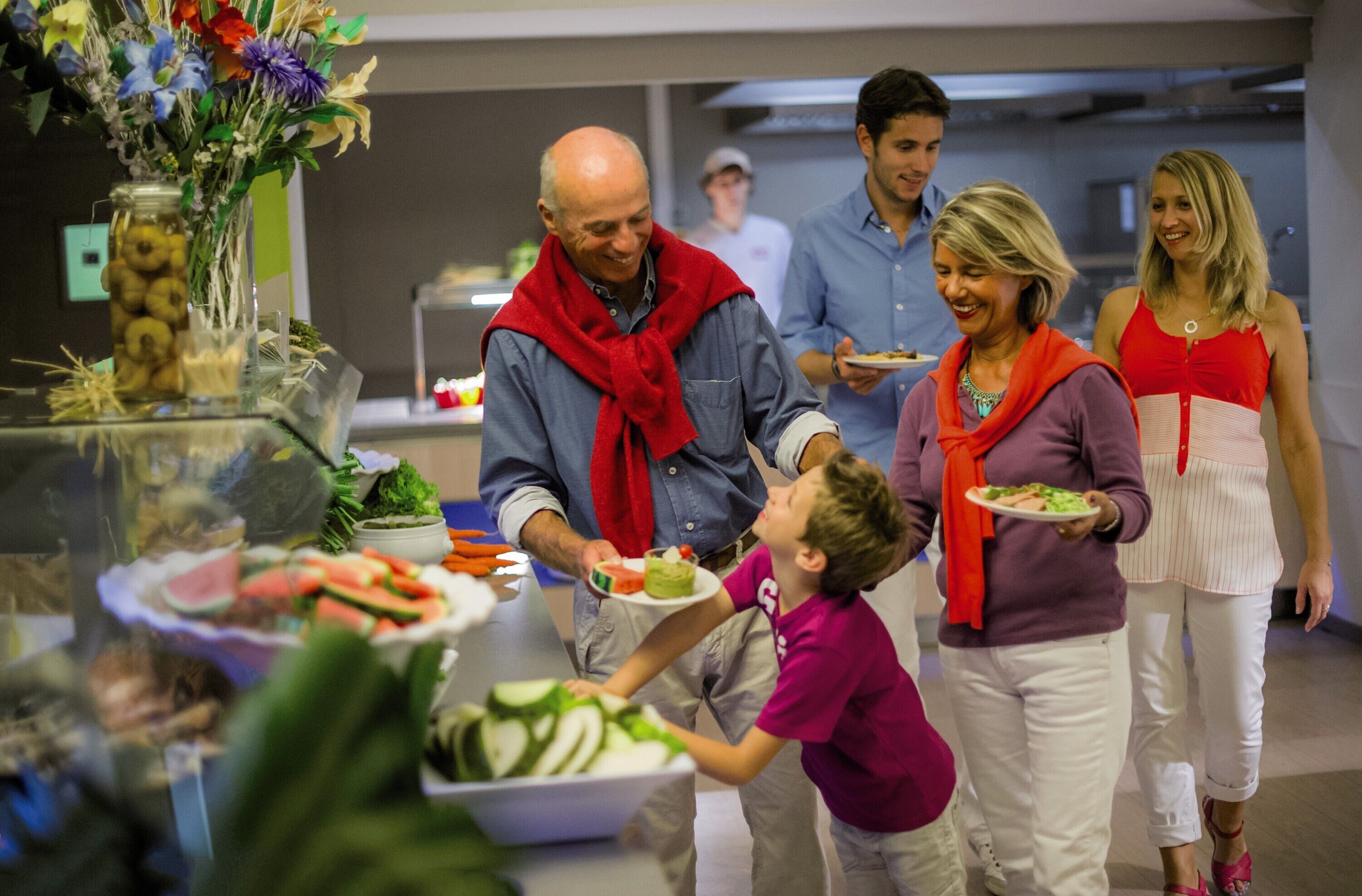 Um buffet com diversos tipos de comida e um vaso decorativo com flores.