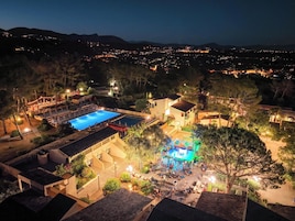 Un complejo turístico con piscina, mobiliario exterior y escenario para eventos.