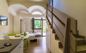 Una habitación de hotel moderna con una escalera, una cama, un escritorio y vistas a zonas verdes.