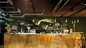 Zona de bar con paneles de bambú, estantes hexagonales e iluminación colgante.