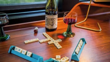Une table en bois, une bouteille de vin, un verre de vin rouge et un jeu de Scrabble.