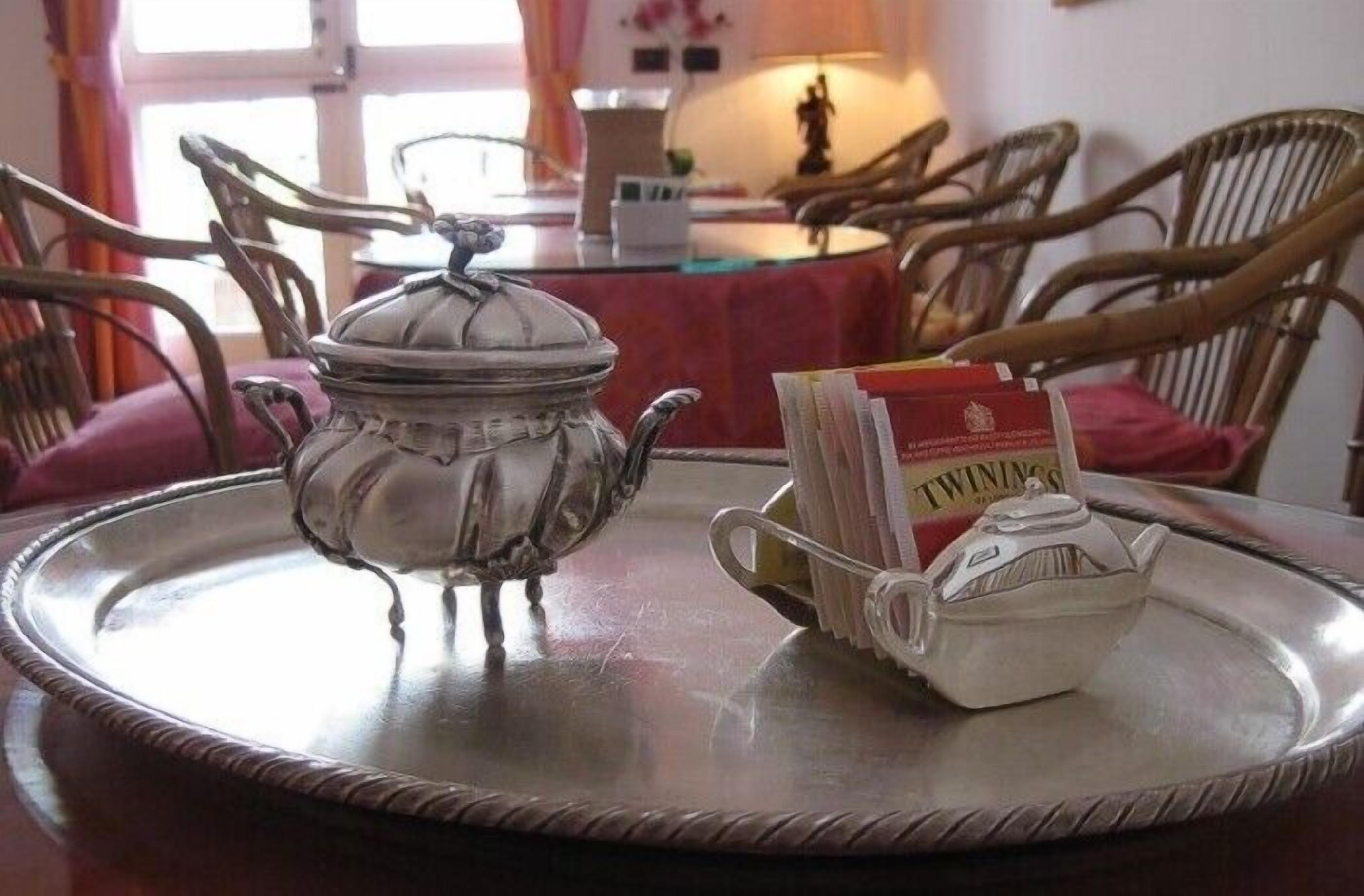 A dining table with a silver tray, a teapot, and a teacup.