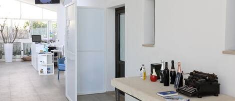 Un espacio de oficina moderno con un escritorio, computadora y varios objetos, incluyendo botellas y una máquina de escribir.