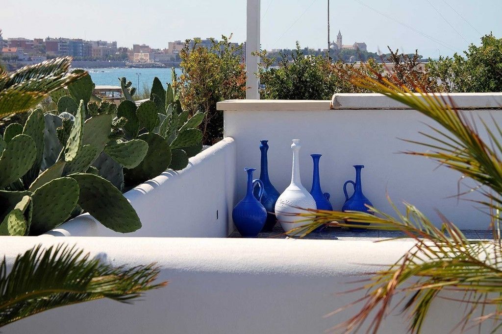 Une terrasse sur le toit, agrémentée de cactus et de vases bleus, d’où l’on peut admirer un panorama sur la ville et la mer.
