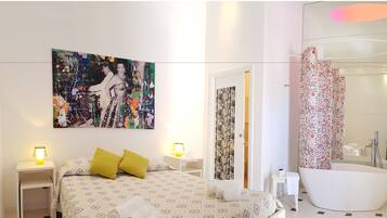 Una habitación de hotel moderna con una cama, un cuadro abstracto grande, un baño con bañera y cortina de ducha.