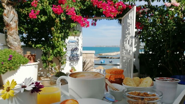 A breakfast table with a slice of cake, a cup of coffee, a jar of honey, a glass of orange juice, and a bowl of cereal.