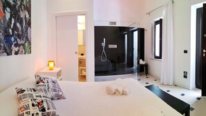A hotel room with a bed, a shower area, and a door.